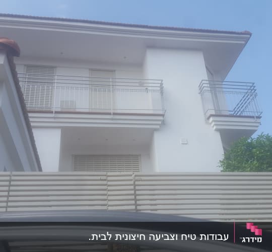 בית לבן עם מרפסת וגדר עץ